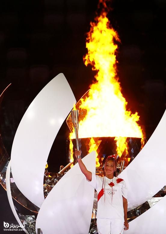 نائومی اوساکا مشعل المپیک را پس از روشن شدن دیگ در مراسم افتتاحیه المپیک توکیو در ژاپن ، 23 ژوئیه 2021 در دست دارد.