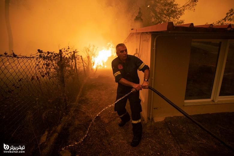 آتش نشان در هنگام سوختن آتش سوزی در روستای پفکی ، در جزیره اوویا ، یونان ، شلنگ می کشد