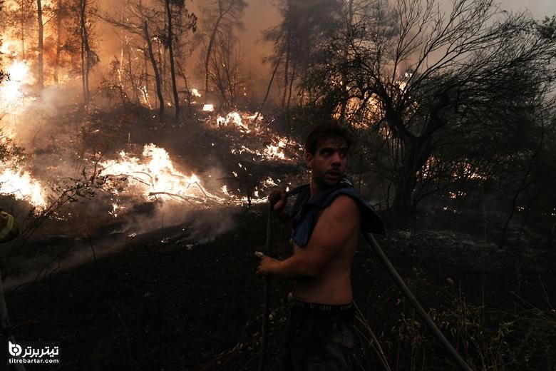 یک مرد شلنگ در دست دارد ، در حالی که آتش سوزی در روستای گوووس ، در جزیره اوویا ، یونان انجام می شود