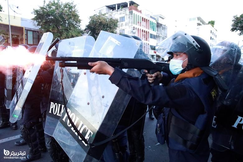 یک افسر پلیس در اعتراض به برخورد دولت با همه گیری کرونا در بانکوک ، تایلند ، سلاح شلیک می کند
