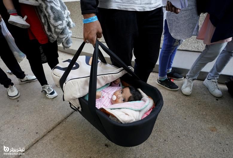 هنگامی که مهاجران افغان سوار اتوبوس می شوند و آنها را به مرکز پردازش می رسانند ، هنگام حمل در فرودگاه بین المللی دالس در دالس ، یک نوزاد حمل می شود.