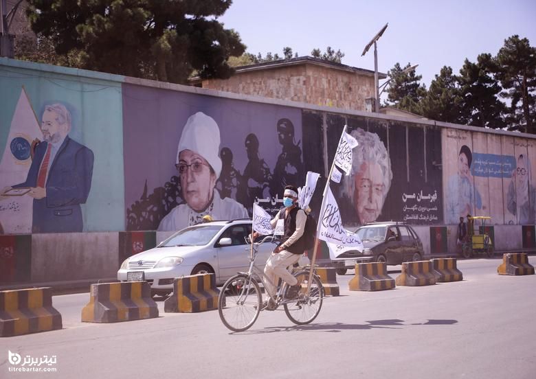 یک مرد افغان در حالی که پرچم طالبان را در کابل در دست دارد با دوچرخه خود سوار می شود