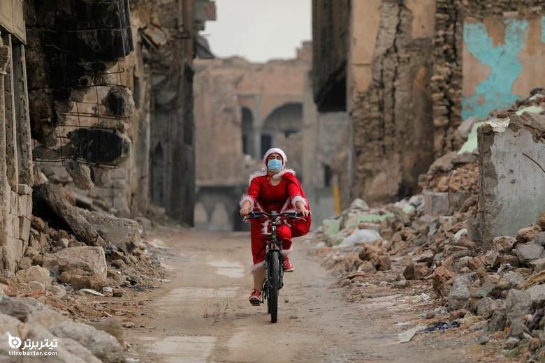 یک زن عراقی با لباس بابانوئل در حال دوچرخه سواری در شهر قدیمی موصل 