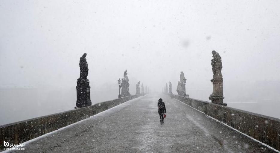 عبور یک زن از روی پل قرون وسطایی چارلز در هنگام بارش برف در پراگ ، جمهوری چک