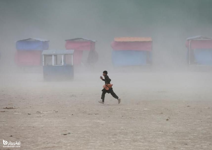 فرار پسر افغانستانی از طوفان گرد و غبار در دریاچه قرغا ، در حومه کابل 