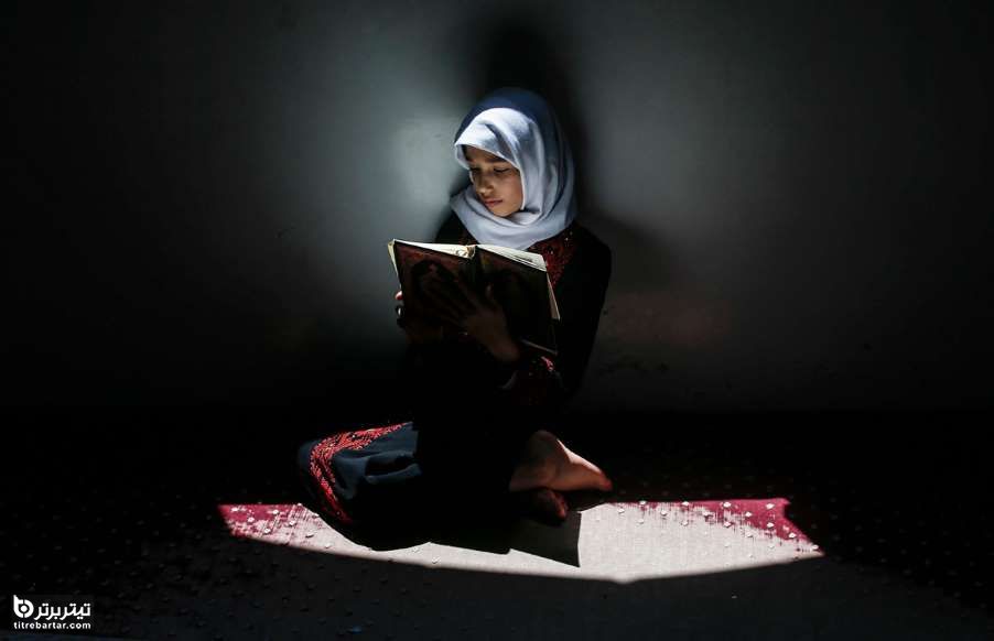 یک دختر فلسطینی ضمن احترام به قوانین مسافت اجتماعی درحال قرآن خواندن در مسجد