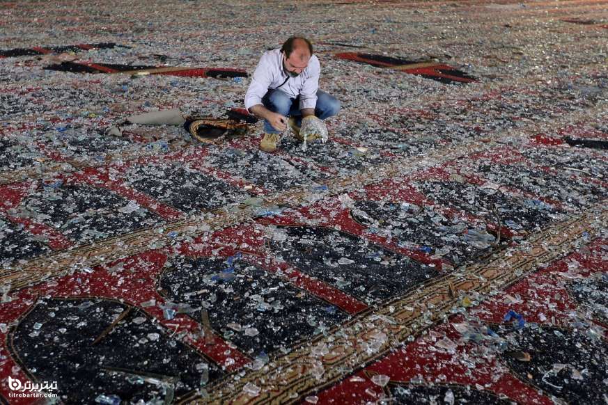 یک مرد درحال جمع کردن شیشه های شکسته شده روی فرش مسجدی در بیروت