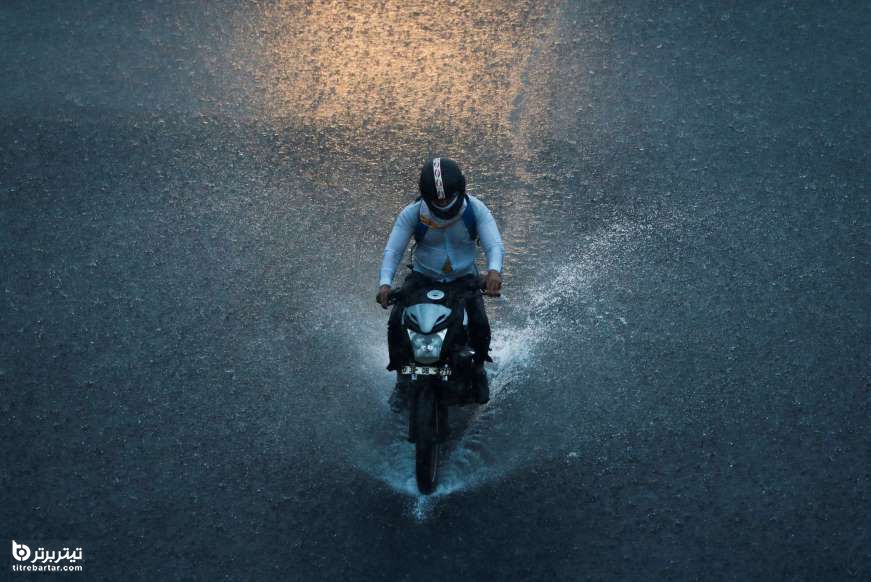 مردی در حال موتور سواری زیر باران شدید در دهلی نو، هند