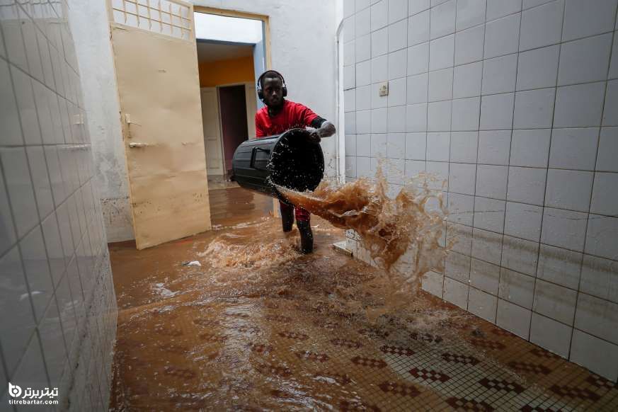 یک داوطلب پس از بارندگی شدید در گودیاوی در حومه داکار ، سنگال ، آب را از یک مرکز بهداشتی در معرض آب گرفتگی خارج می کند