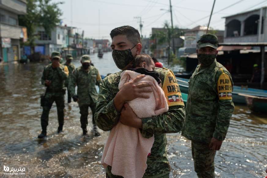 سرباز مکزیکی یک نوزاد را حمل می کند